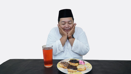 Portrait of overweight muslim man with head cap or songkok pray before eat and drink for islam break fasting