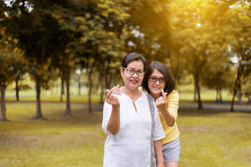 Couple asian woman hands showing mini heart and relax at public park in the morning together,Happy and smiling,Positive thinking,Healthy and lifestyle concept