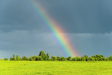 Rural landscape with rainbow in the sky after the rain.