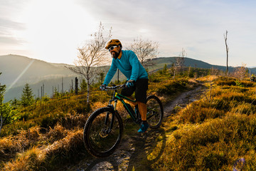 Fototapeta na wymiar Cycling man riding on bike at sunset mountains forest landscape. Cycling MTB enduro flow trail track. Outdoor sport activity.