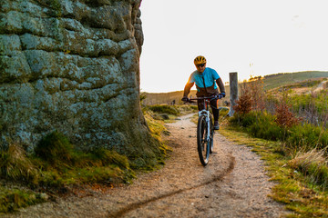 Fototapeta premium Mountain biking woman riding on bike in summer mountains forest landscape. Woman cycling MTB flow trail track. Outdoor sport activity.
