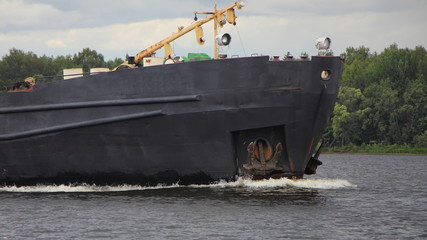 Floating black cargo ship's bow stem dissects water, commercial shipping, marine logistics