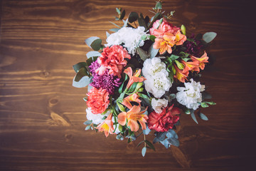 Bouquet of pink, white, orange, lilac and many colorful flowers on a wooden table. Wedding decoration.