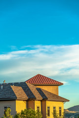 Home exterior view on a sunny day with mountain and cloudy blue sky background