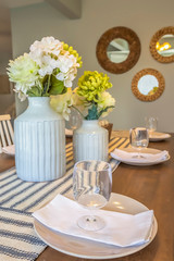 Dinnerware and flowers on a brown wooden dining table with table runners