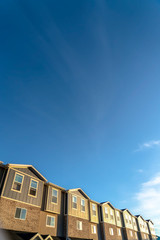 Blue sky over row of houses with wood brick and concrete exterior wall
