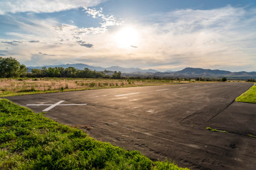 Road with view of field and mountain under cloudy blue sky on a sunny day