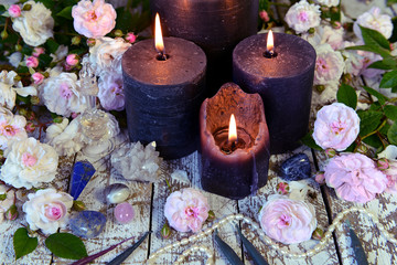 Still life with burning black candles and white roses.