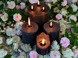 Still life with black candles and roses on green witch table.