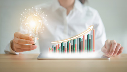 Businesswoman holding light bulb with innovative and creativity are keys to success. chart showing...