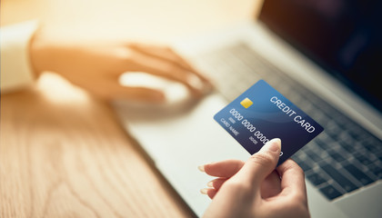 Hand holding credit card and press laptop computer enter the payment code for the product. Pay online for convenience.