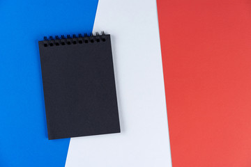 Blacklist France. Mourning, ban, sanctions, politics. black notebook lies on French flag. Mock up, copy space, pattern, cardboard texture.