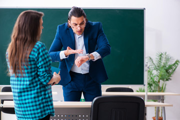 Young handsome teacher and female student in the classroom