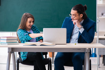 Young handsome teacher and female student in the classroom