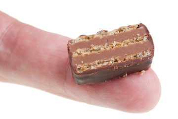 In the future we will eat this concept - little ugly slice of chocolate cake on finger isolated macro