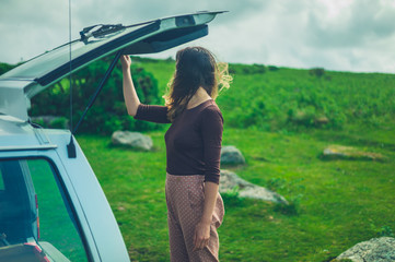 Young woman opening the trunk of her car in nature