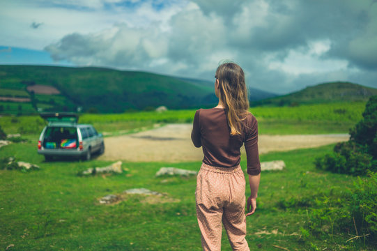 Young woman with parked car walking in nature