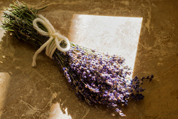 Obraz na płótnie Canvas Lavender. A bouquet of lavender on a marble table tied with white thread. Lit by the sun