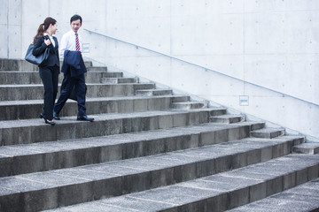 階段を下るビジネスマンとビジネスウーマン