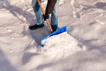 A teenager shoveling snow in his yard. The concept of a snowy winter. © Aliaksandr