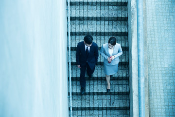 階段を下るビジネスウーマンとビジネスマン