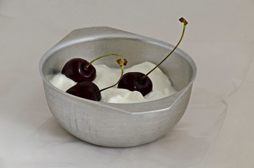 Three ripe fresh red cherries with stalks on yoghurt in a bowl, Sofia, Bulgaria 