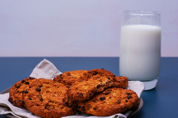 Chocolate breakfast cookies with a glass of milk on a turquoise table