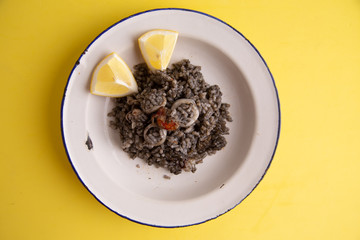 Plate of black rice with squid and prawns or Valencian black paella