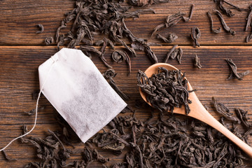 Tea in a wooden spoon and a tea bag. Loose tea in a spoon and tea bag on a wooden background.