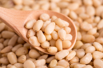 Pine nuts close up. Pine nuts in a wooden spoon. Peeled Pine Nut.