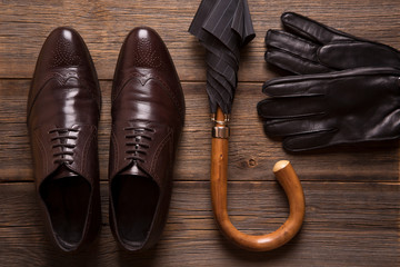 Umbrella and men shoes close-up. Rain umbrella. Men shoes, gloves and umbrella cane on a wooden background.