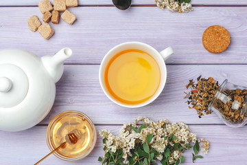 Cup of tea with sugar cubes and flower branches on wooden table close up