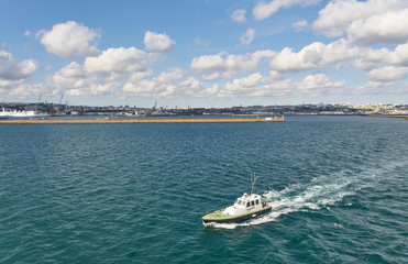 Naklejka premium The French Pilot Boat escorting a Vessel out of Brest Harbour, and into Open seas on a fine Spring Day.