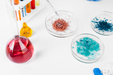 Colored liquids inside lab glassware on white table in laboratory