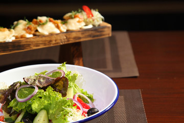 Dumplings with potatoes and greaves in sour cream on a wooden board and salad. Dumplings with potatoes and salad.