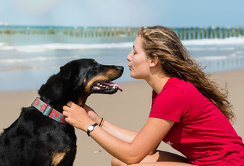 beautiful young woman and her dog playing on the beach