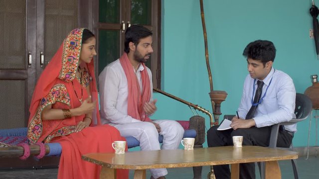 Young government employee collecting information from villagers - survey concept. Indian government official gathering census data from the villagers - Husband and Wife