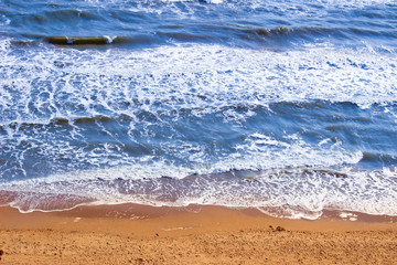 Sea coast with yellow sand and foamy waves