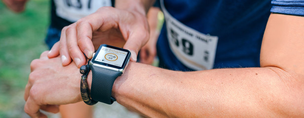 Unrecognizable sportsman looking at a smartwatch during a race
