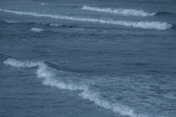 Marine background of dark blue aqua sea water surface splashing outside. Horizontal color photography.