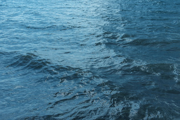 Blue water with waves and sun reflections background