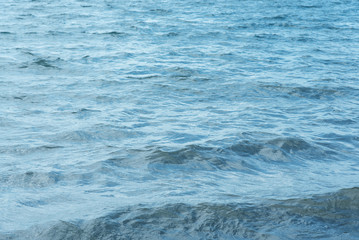 Blue water with waves and sun reflections background
