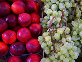  Display of red peaches and green grapes at the Italian fruit market. Closeup for background. 