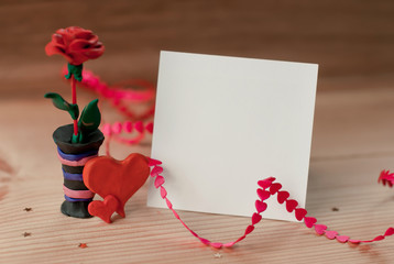a piece of paper for the message among the heart and roses of plasticine on a  table