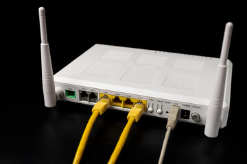 White internet router with connected yellow and white usb wire are on the black table/background....