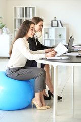 Young businesswomen sitting on fitballs while working in office