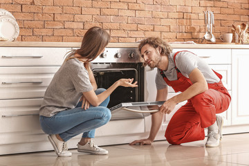 Worker repairing oven in kitchen