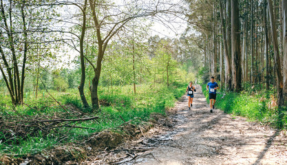 Obraz premium Young woman and man participating in a trail race through the forest