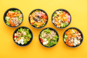 Many containers with delicious food on color background