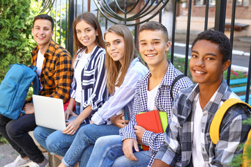Young students sitting on bench outdoors